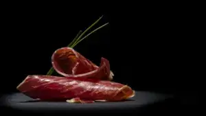 Lonchas de jamón ibérico de bellota gourmet con grasa translúcida en fondo oscuro