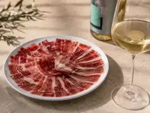 Jamón ibérico servido con una copa de vino blanco